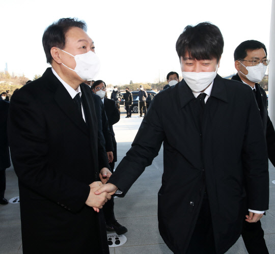 지난 1월1일 국민의힘 윤석열 대선 후보와 이준석(오른쪽) 대표가 1일 오전 서울 동작구 국립서울현충원을 참배하기 전 만나 악수하고 있다.연합뉴스